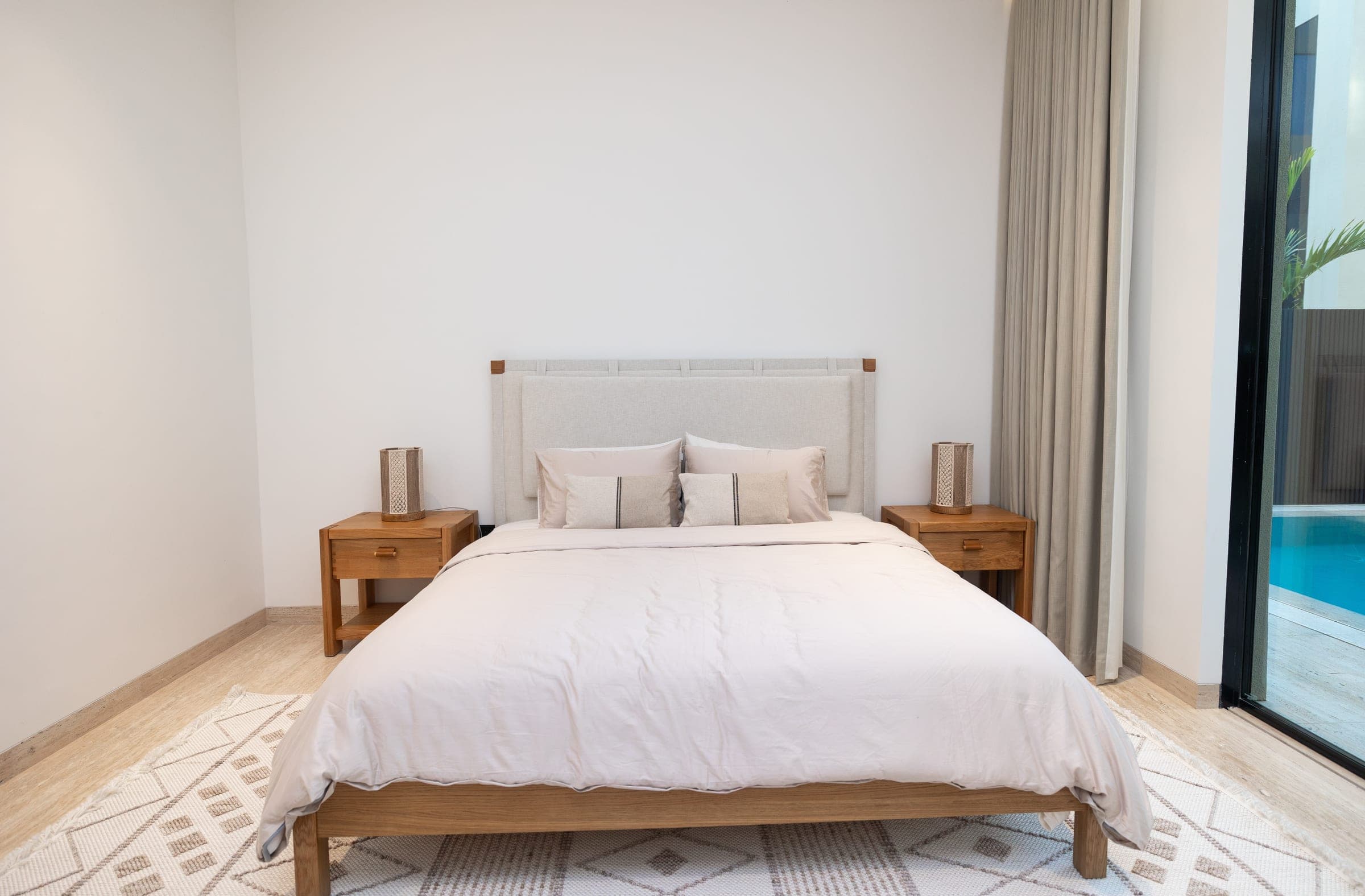 Bedroom with a patterned rug, timber nightstands and sheer curtains at Sand House, a LKYOOB commission