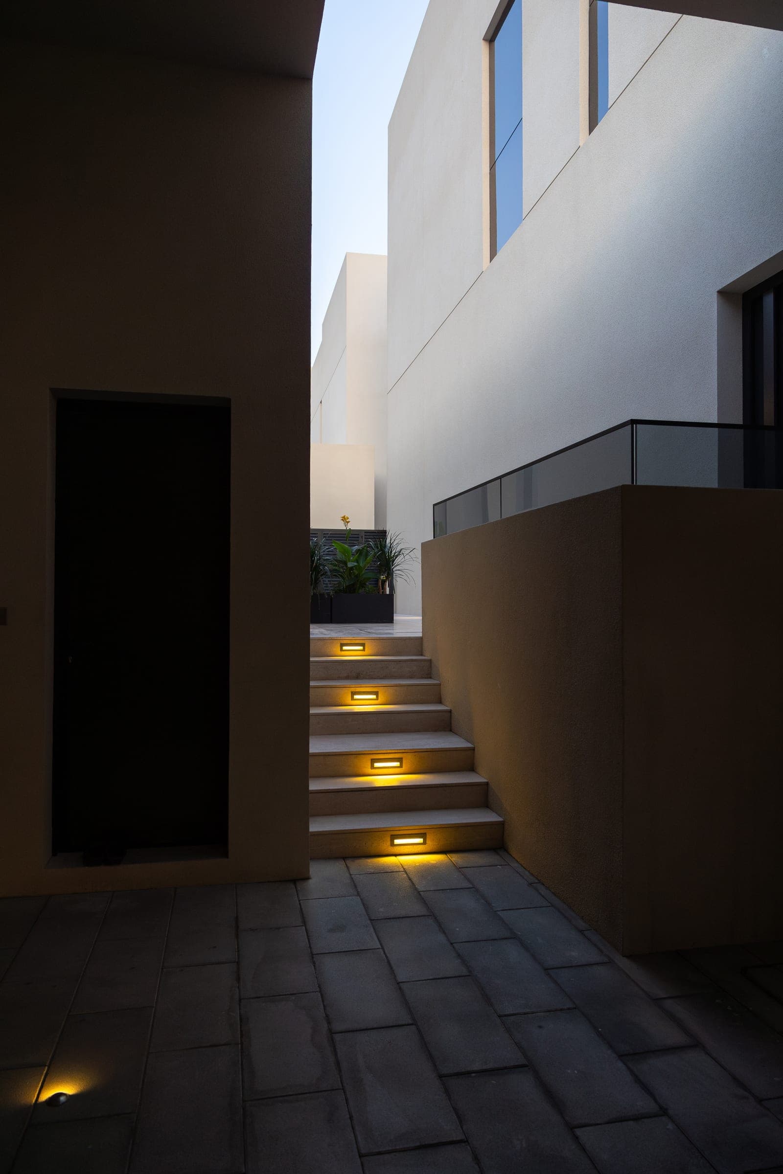 Passage of lit steps along the side of Sand House at dusk, a LKYOOB commission