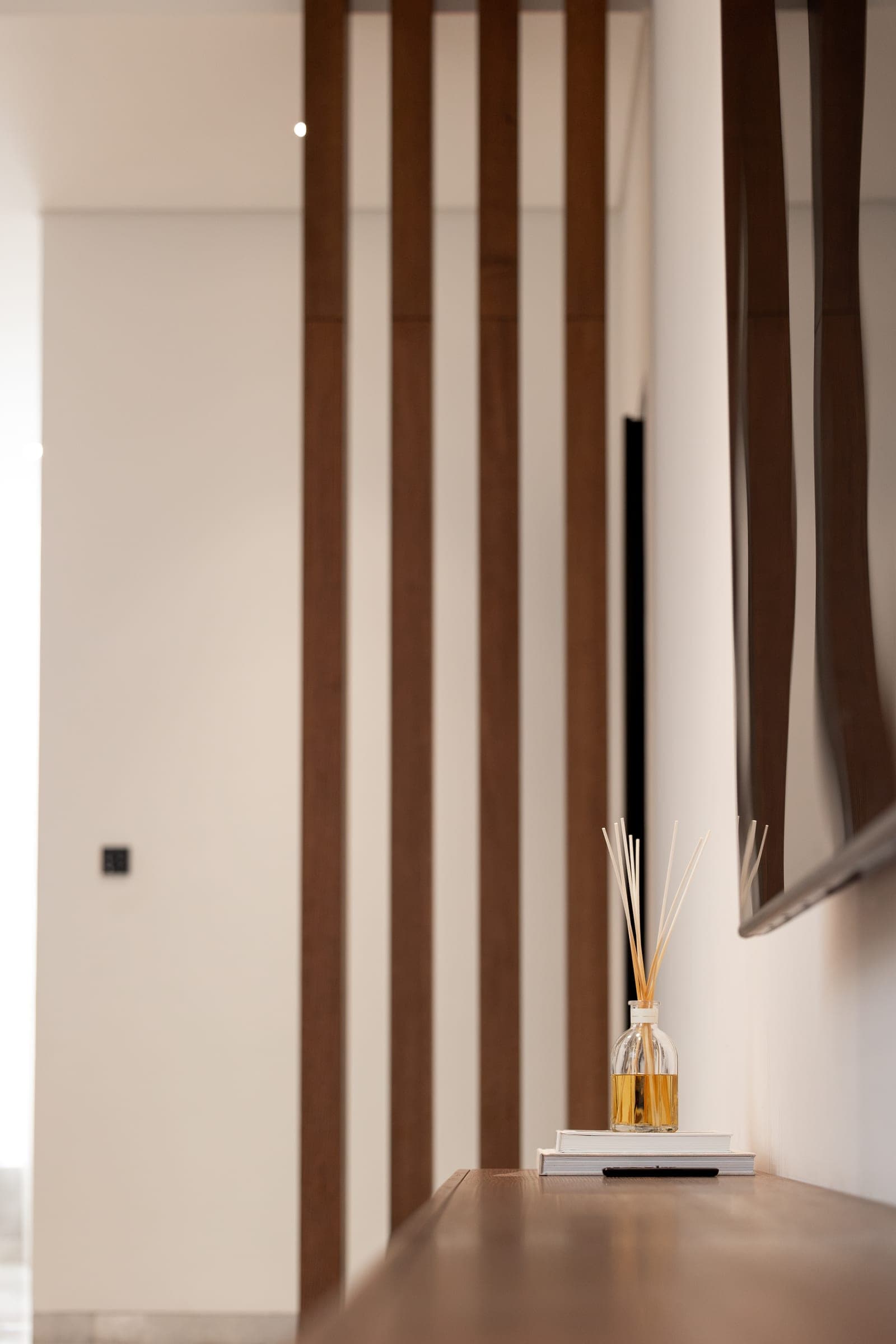 Walnut fins beside a passage, with a diffuser on a timber ledge, at The Cube 61, a LKYOOB commission
