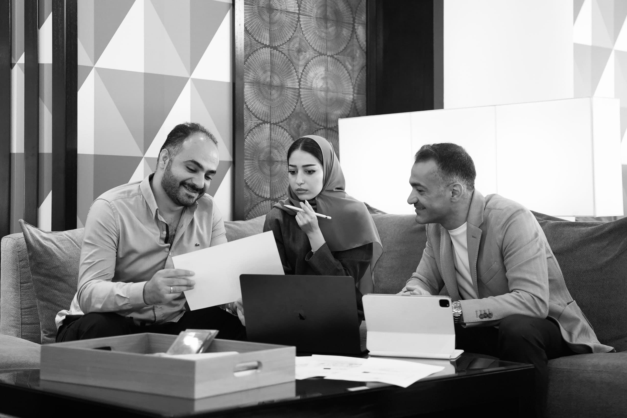 The LKYOOB team in a working session — reviewing drawings over a laptop and tablet with material boards on the table — senior architects and designers