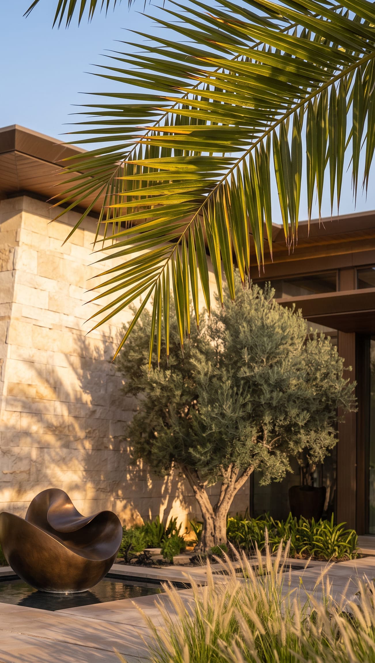 Design visualisation of an olive tree and a bronze sculpture beside the stone wall under a palm, by LKYOOB