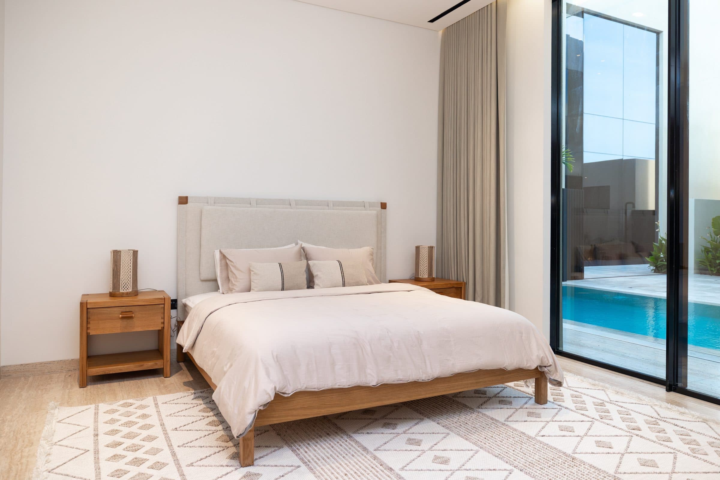 Bedroom with a timber bed and full-height glazing onto the courtyard pool at The Travertine Villas, a LKYOOB commission