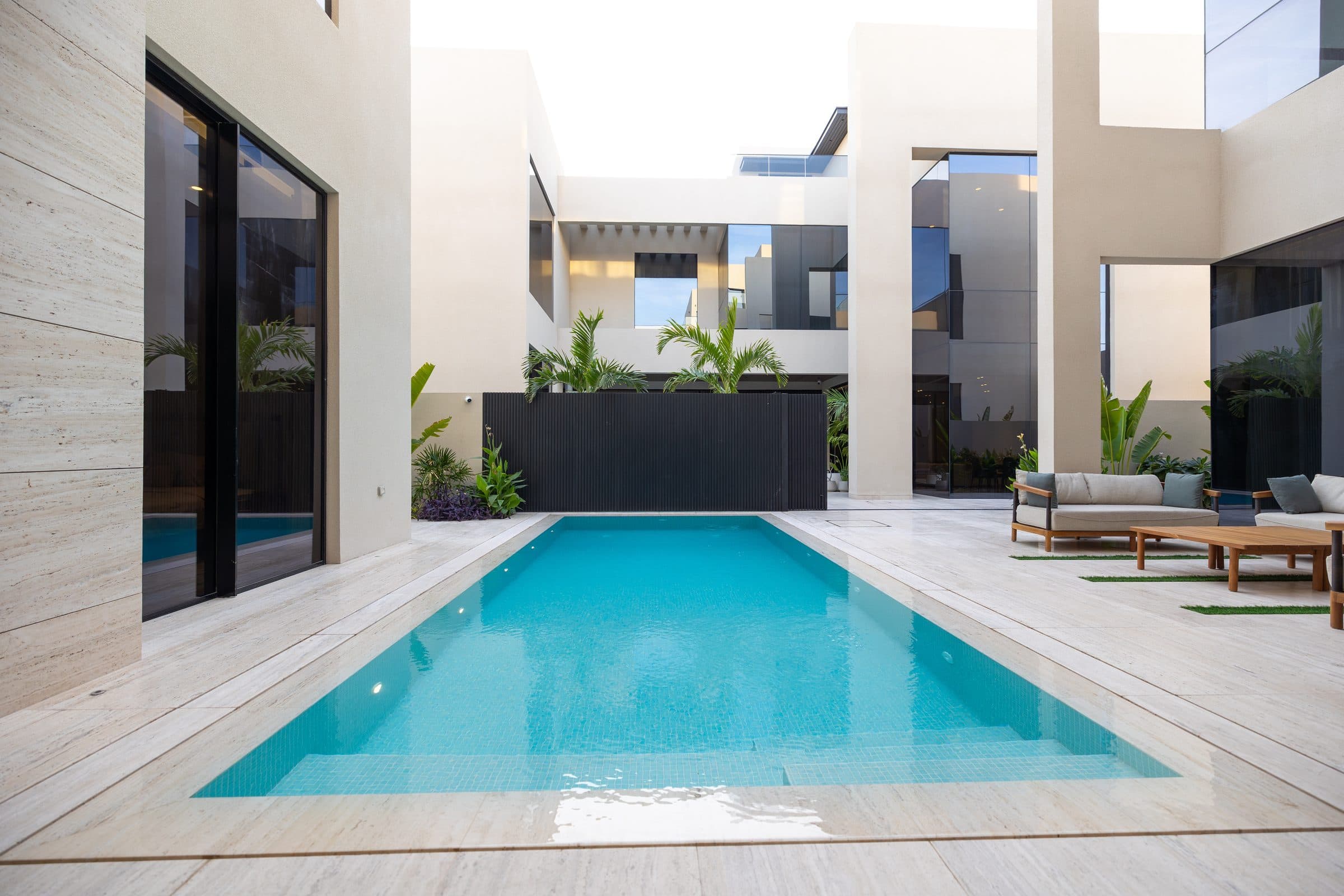 Courtyard swimming pool set between villa volumes with planting, at The Travertine Villas, a LKYOOB commission