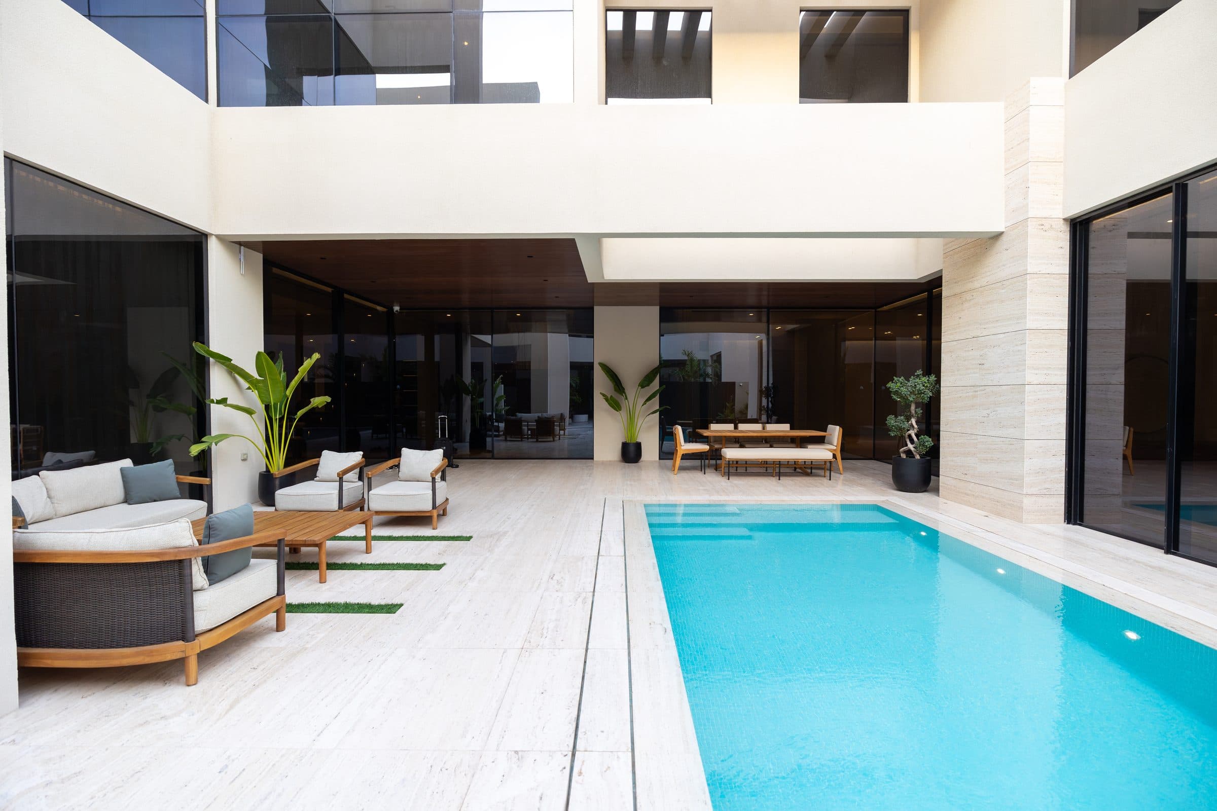 Pool terrace with loungers beneath a double-height shaded colonnade at The Travertine Villas, a LKYOOB commission