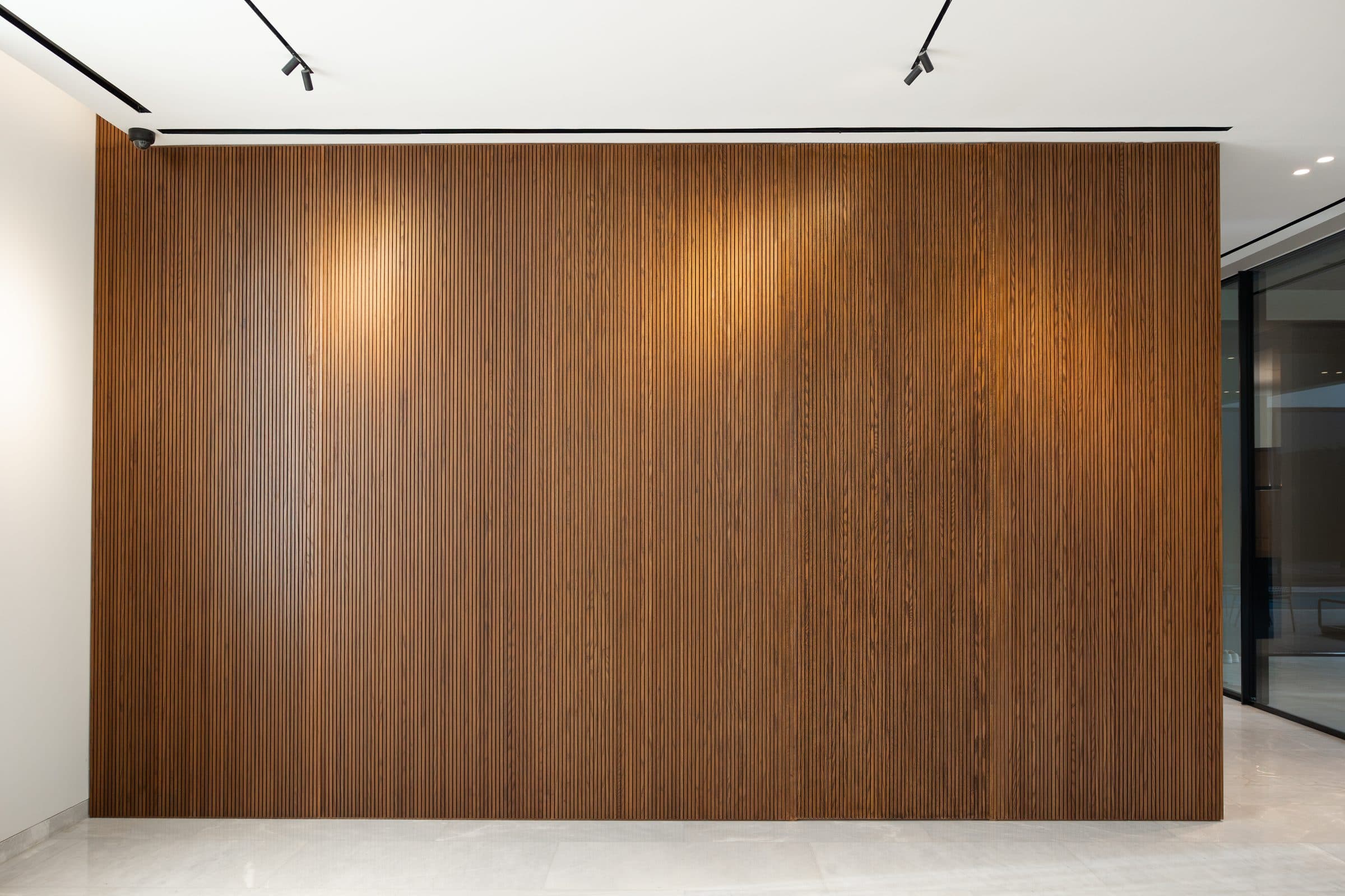 Fluted walnut joinery wall beside full-height glazing at The Travertine Villas, a LKYOOB commission