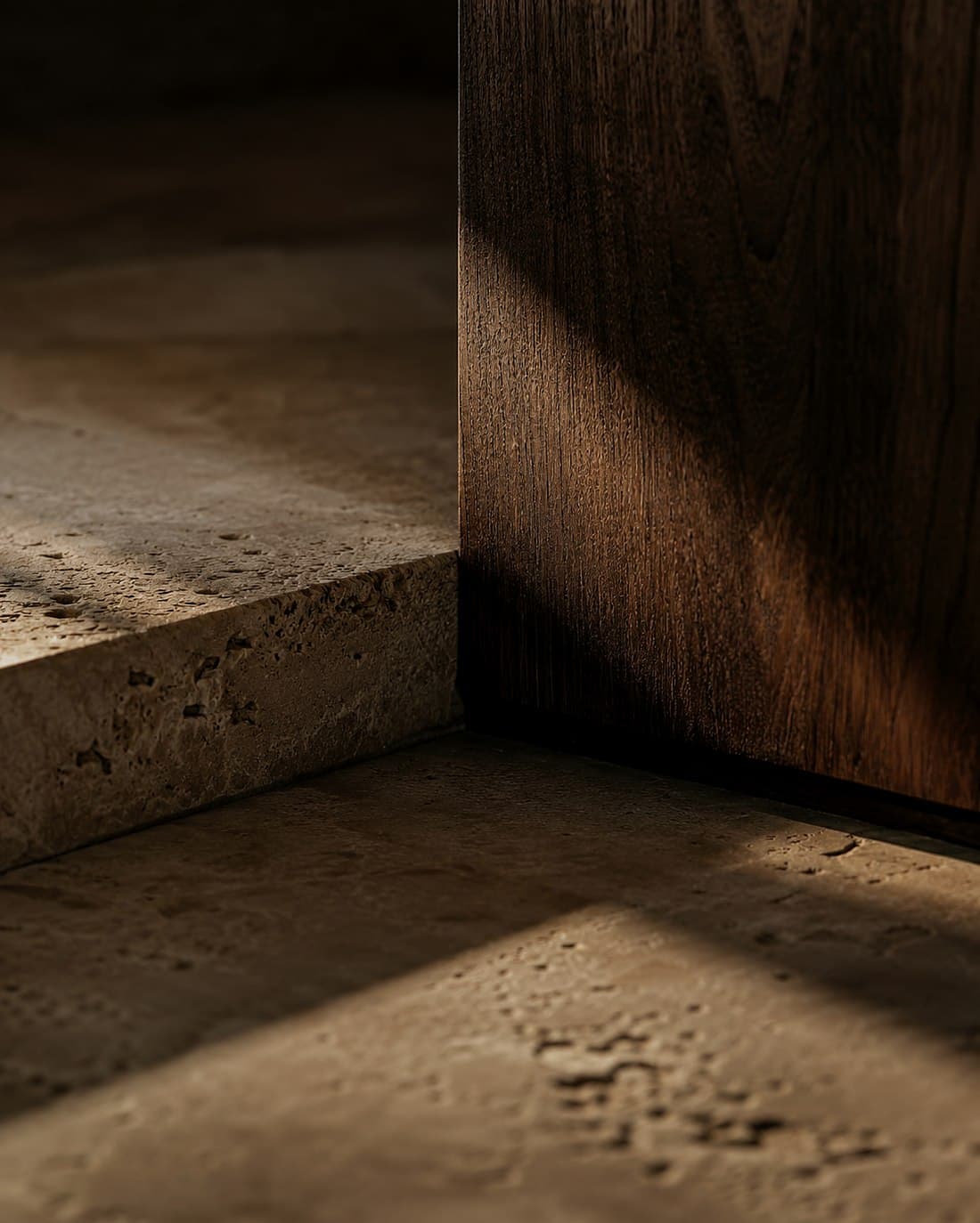 A detail where travertine meets walnut under directed light